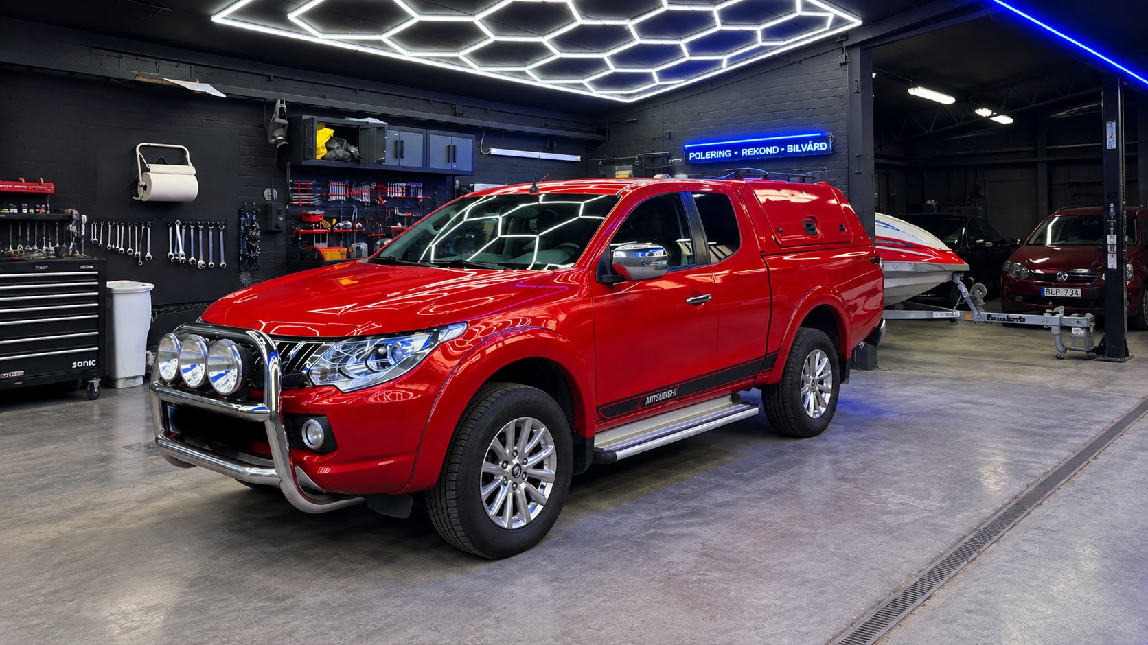 Röd Mitsubishi L200 efter polering, hexagonlamporna speglas skarpt i lacken
