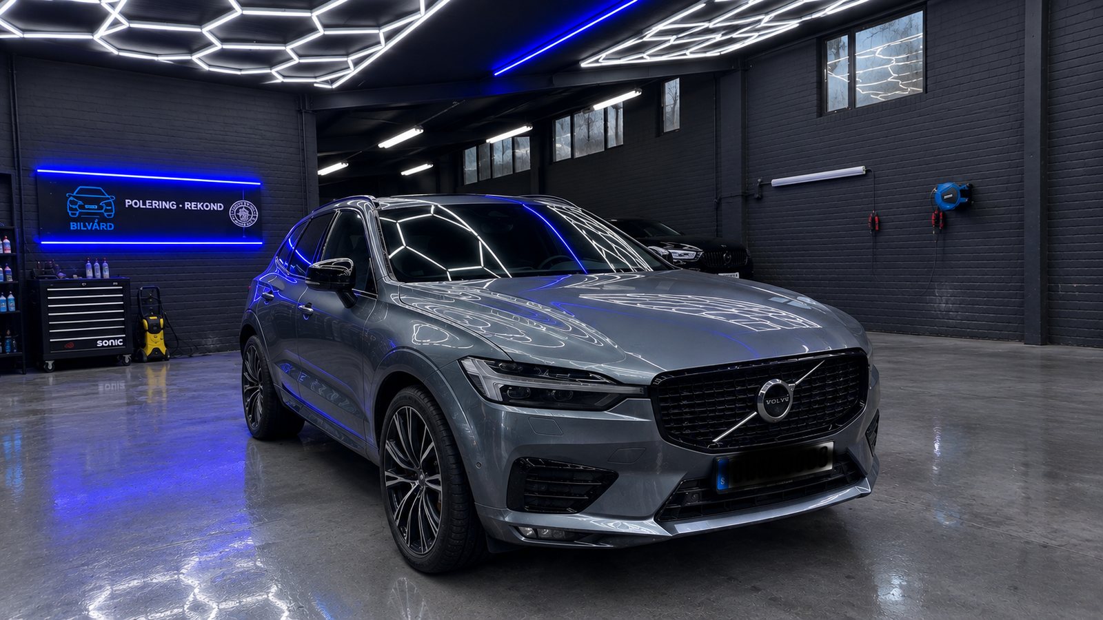 Polerad Volvo XC60 i verkstaden med hexagonbelysningen speglad i lacken